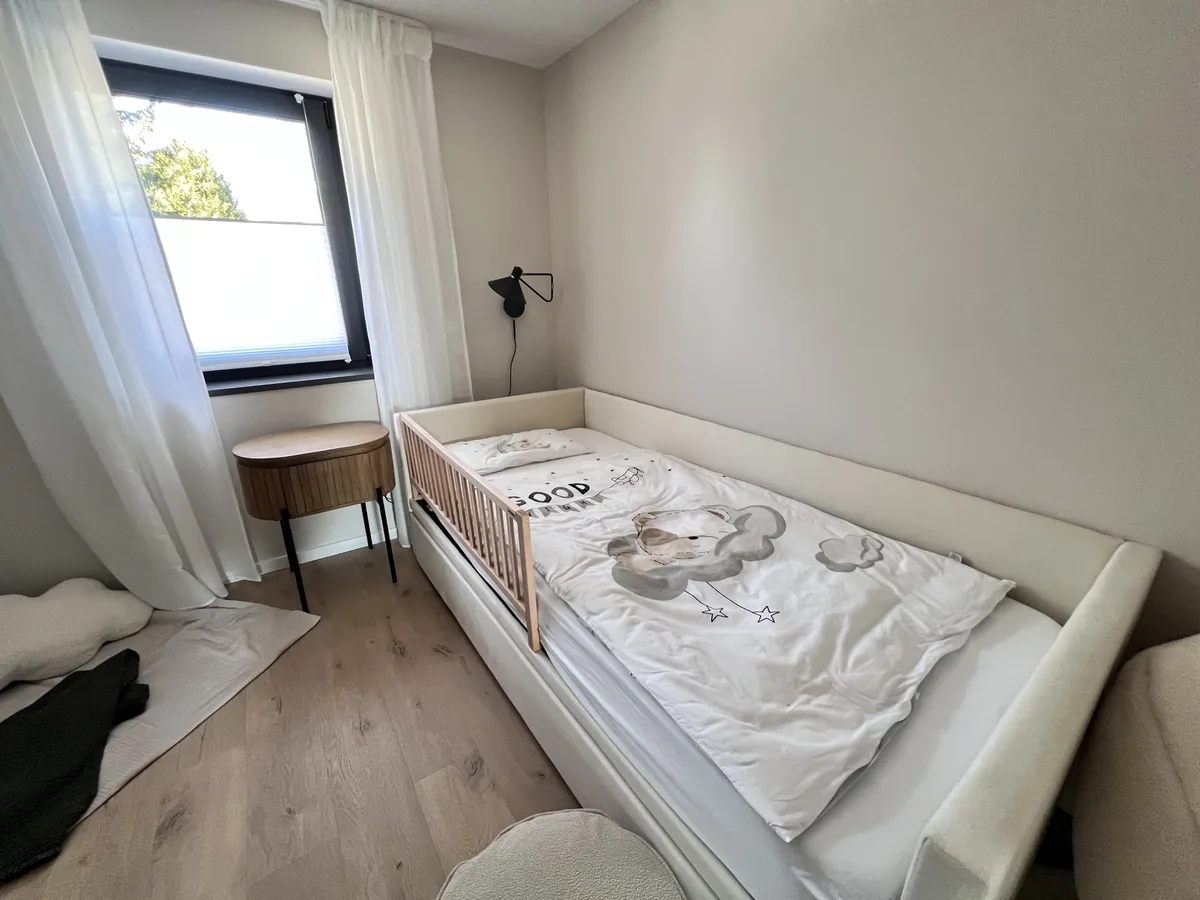 Einzelbett mit hölzernem Rausfallschutz und Kinderbettwäsche im zweiten Schlafzimmer des WolkenGarten