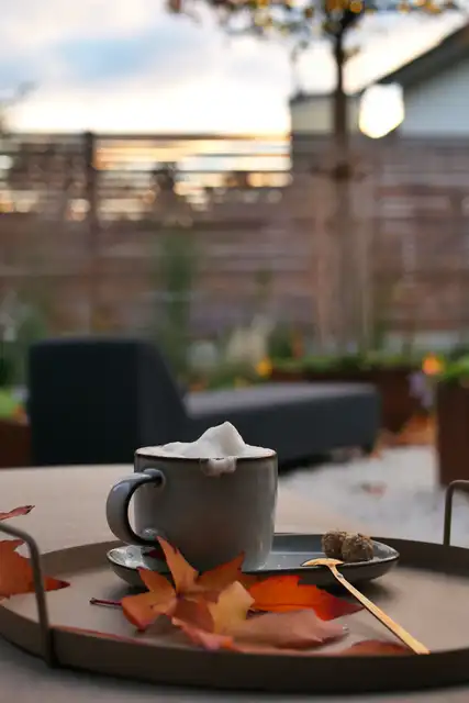 Kaffee auf der Terrasse mit Herbstlaub, im Hintergrund die Lounge