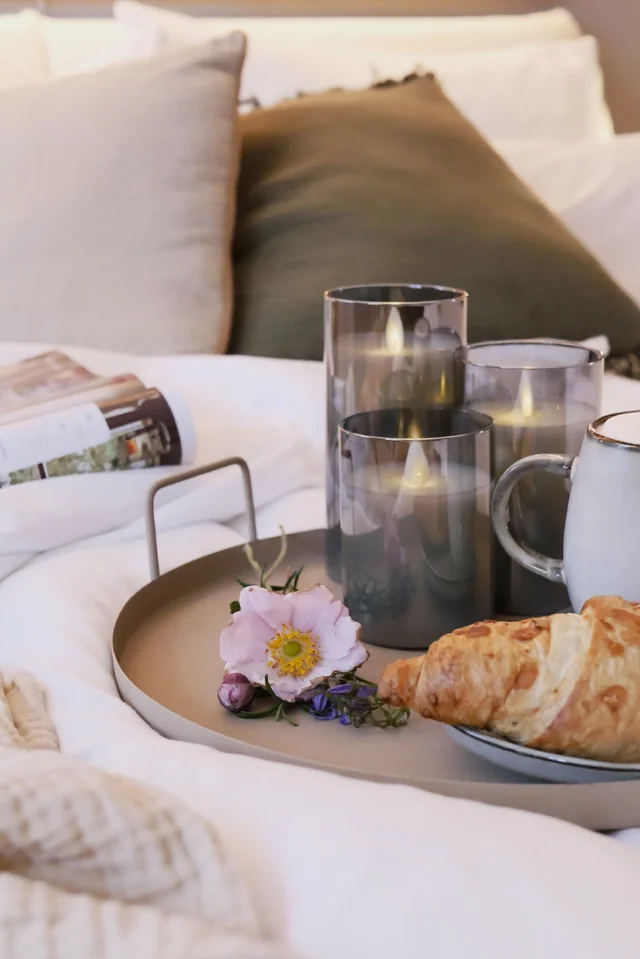 Frühstückstablett mit Croissant auf dem Bett am Sonntagmorgen