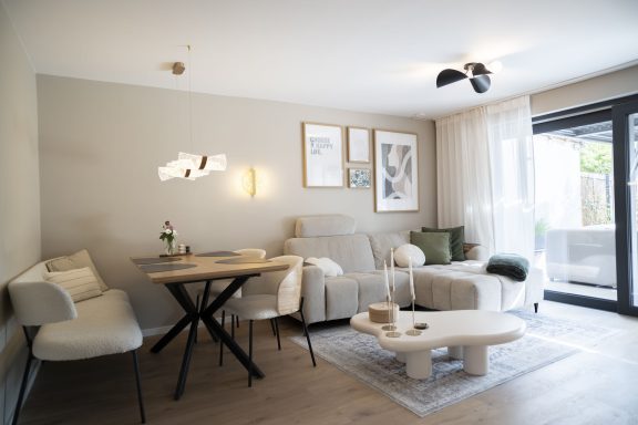 Ausziehbarer Esstisch Helle Wohnzimmereinrichtung mit Sofa, Tisch und Accessoires in neutralen Farben.