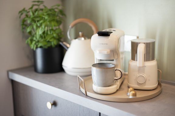 Nespresso, Dolche Gusto und Siebträger Küchenzeile mit einer Kaffeemaschine, Teekanne und einer Tasse auf einem Tablett.