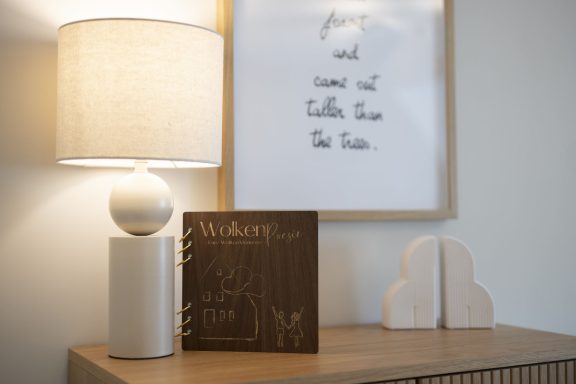 Gästebuch Ein Nachttisch mit einer Lampe, einem Buch und dekorativen Objekten.