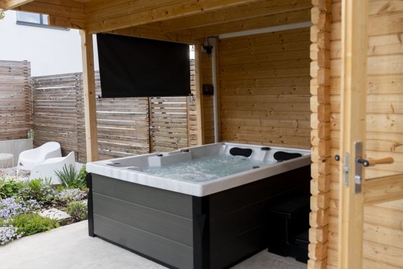 Outdoor Whirlpool Überdachter Outdoor Whirlpool mit Sichtschutz Blick auf den Garten.