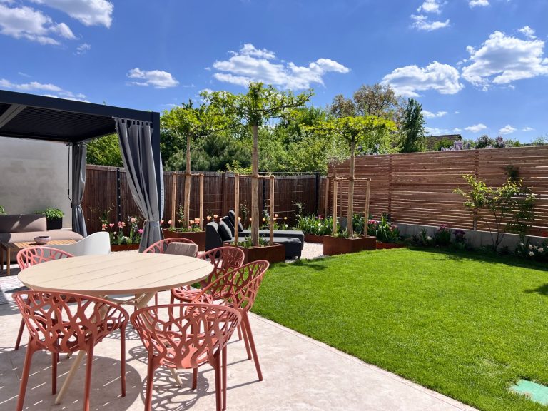Moderne Gartenansicht mit beleuchteten Bäumen, einer Terrasse und eleganten Möbeln.