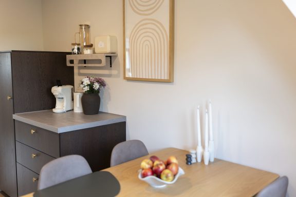 Esstisch für bis zu 4 Personen Moderne Küche mit Holztisch, Obstschale und minimalistischer Dekoration.