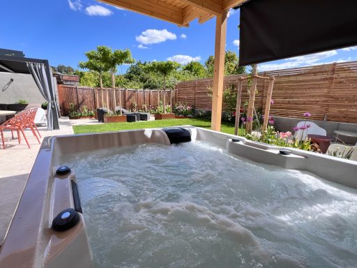 Whirlpool im Freien mit sprudelndem Wasser, umgeben von einem gepflegten Garten.
