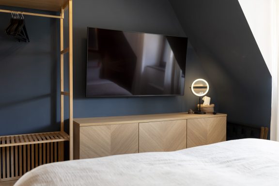 Fernseher und Schank Moderner Raum mit Fernseher, Kommode aus Holz und akzentuiertem Wandanstrich.