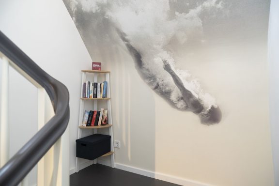 Bibliothek und Spiele im Treppenhaus Wand mit Wolkenmuster und einem Bücherregal in einer Treppenhaus-Ecke.