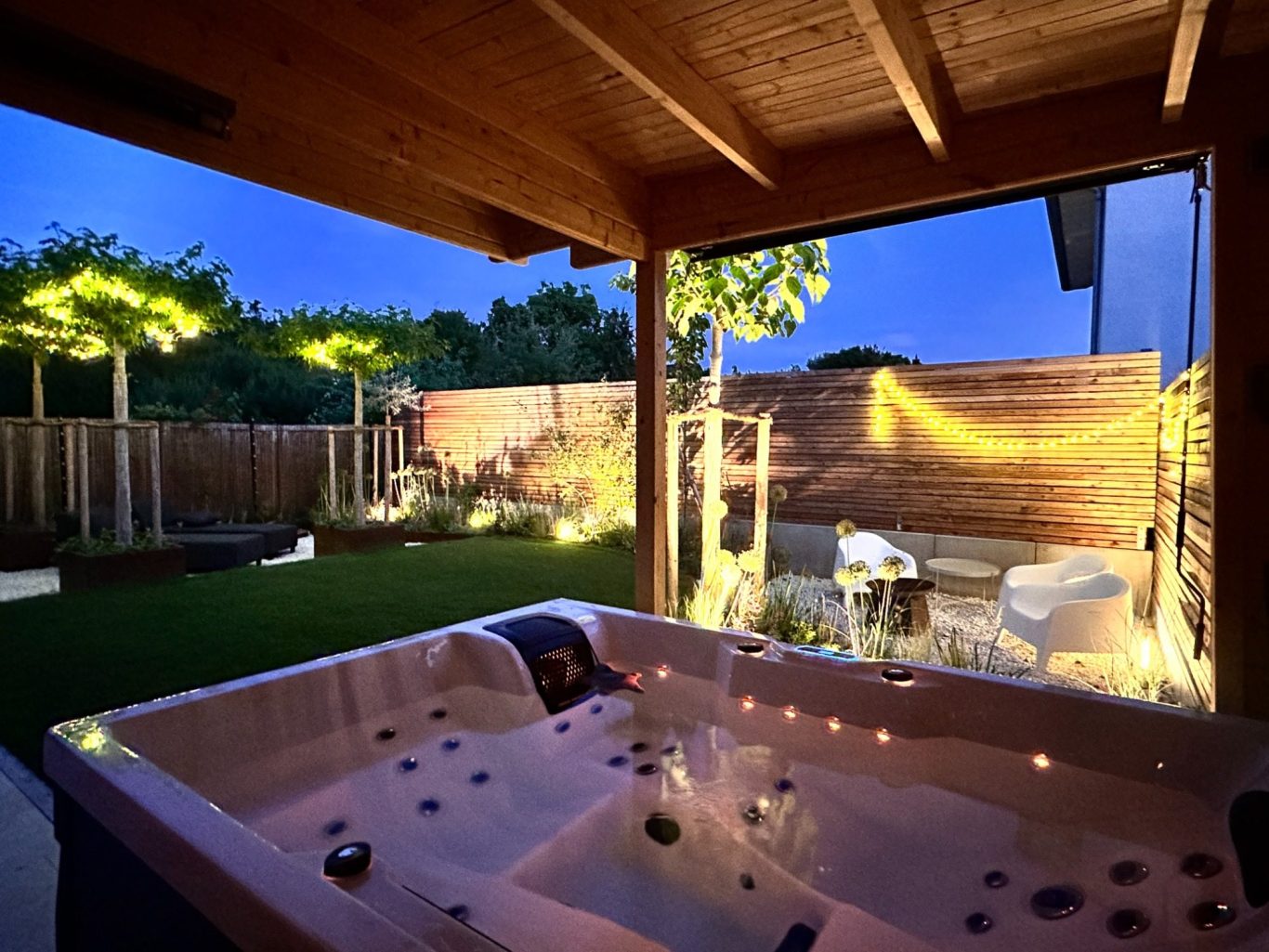 Whirlpool Entspannender Außenbereich mit Whirlpool, sanfter Beleuchtung und grünem Garten.