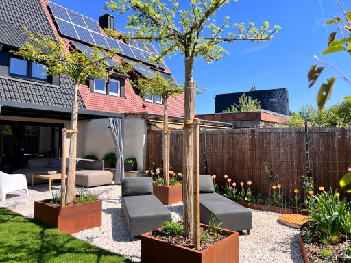 Moderne Gartenlandschaft mit Sonnenliegen, Bäumen und blühenden Pflanzen unter blauem Himmel.