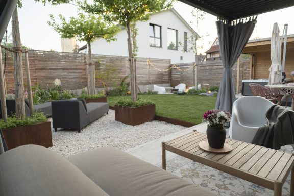 Garten Gemütlicher Garten mit Sitzbereich, Rasen und blühenden Pflanzen.
