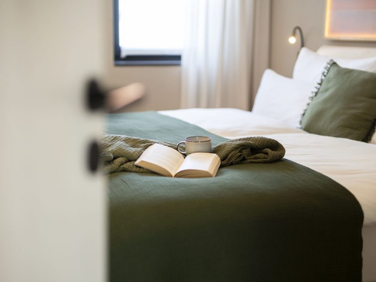 Masterbedroom Ein gemütliches Schlafzimmer mit einem Buch auf der Bettdecke in grünen Farbtönen.