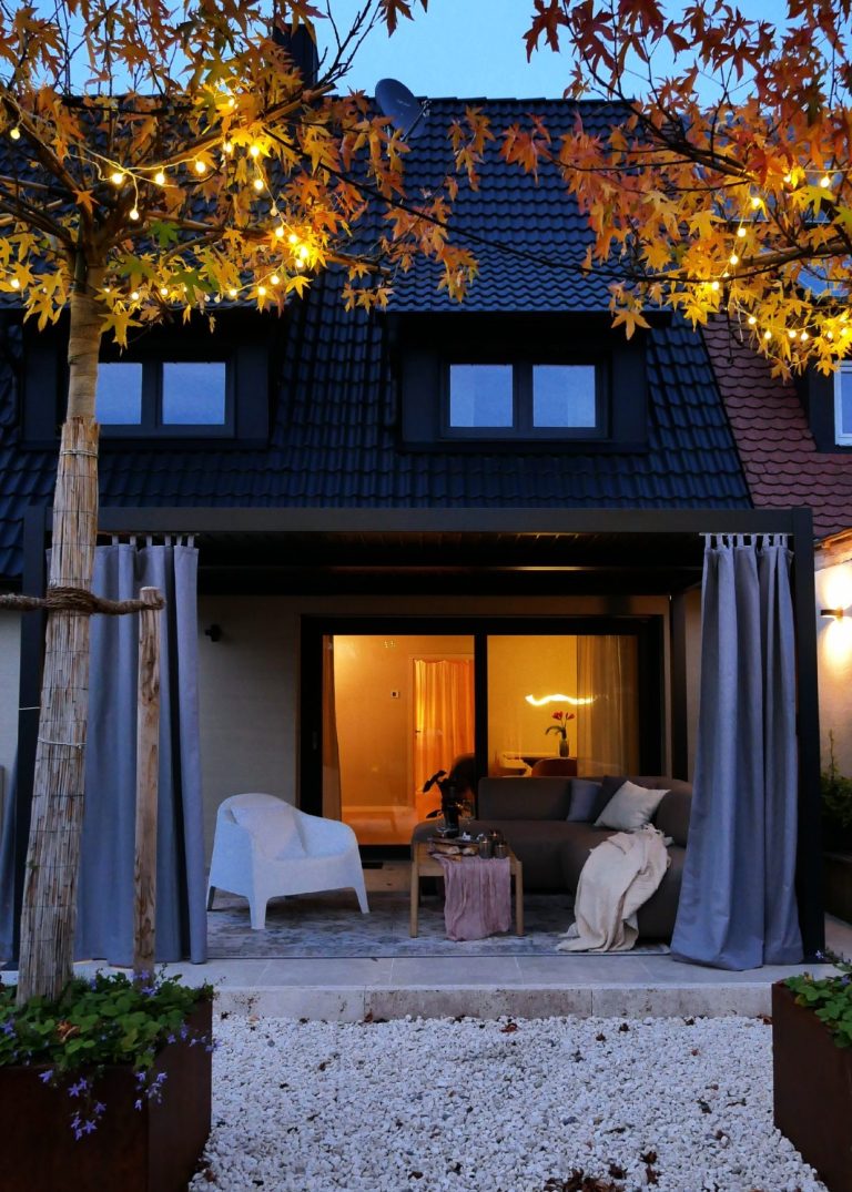 Terrasse Lounge Gemütlicher Außenbereich eines Hauses mit stimmungsvollem Licht und herbstlichen Blättern.