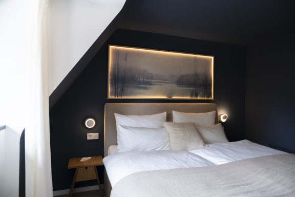 Schlafzimmer WolkenBlick Helles Schlafzimmer mit einem großen Bett, Kunstwerk über dem Kopfteil und gemütlicher Atmosphäre.