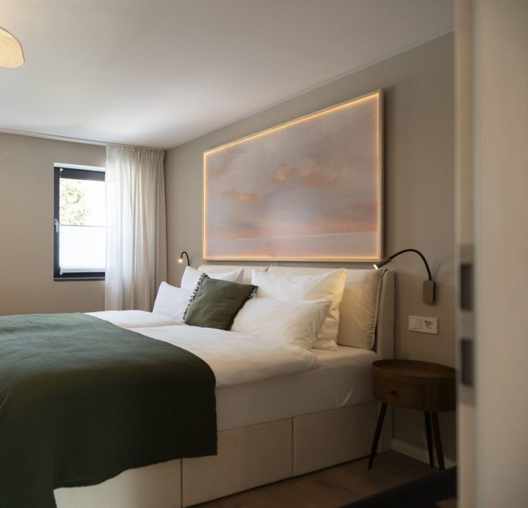 Schlafzimmer WolkenGarten Gemütliches Schlafzimmer mit grünem Bettüberzug und sanfter Beleuchtung.
