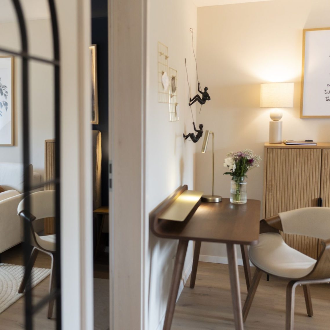 Schreibtisch mit Dekoration Beleuchteter Wohnraum mit einem Tisch, Stühlen und einer Blumenarrangement.