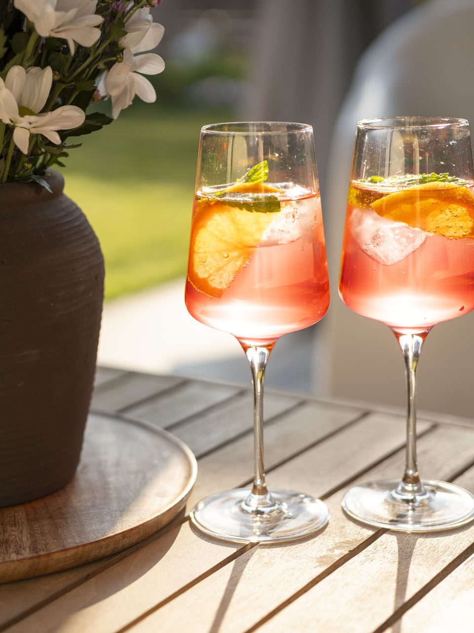 Zwei Gläser mit Aperitif und Orangenscheiben auf dem Gartentisch