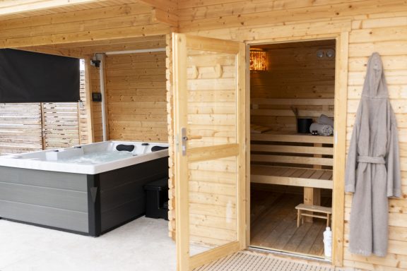 Whirlpool & Sauna Sauna mit angeschlossenem Whirlpool, Holzverkleidung und Bademantel an der Tür.